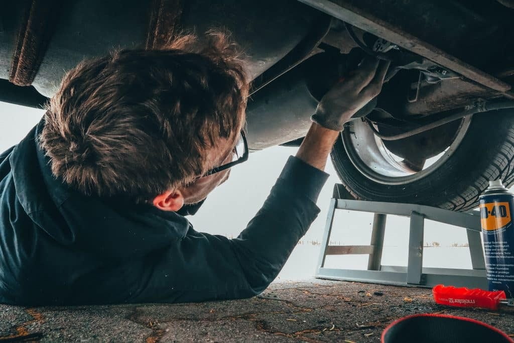 A man is working on the underside of a car.
