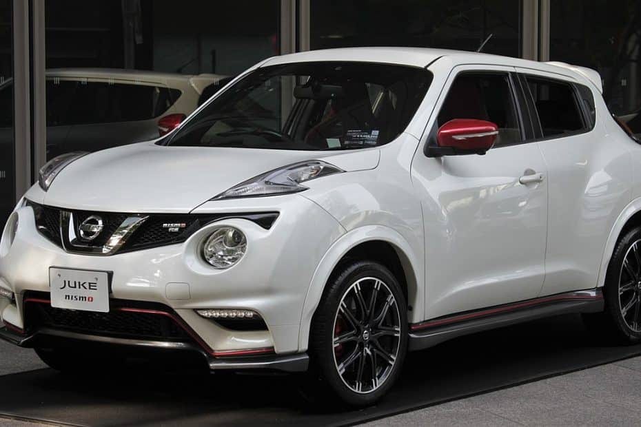 A white nissan juke parked in front of a building.