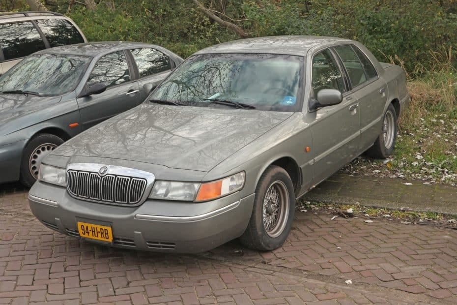A gray car parked on a brick driveway.