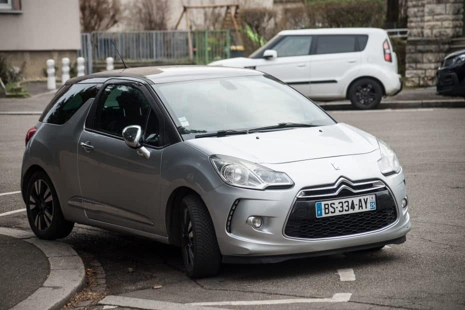 A small silver car parked on the side of the road.