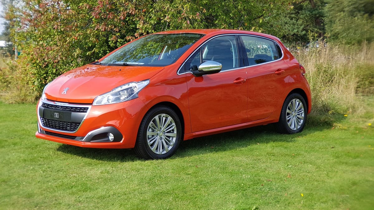 A small orange car parked on a grassy field.