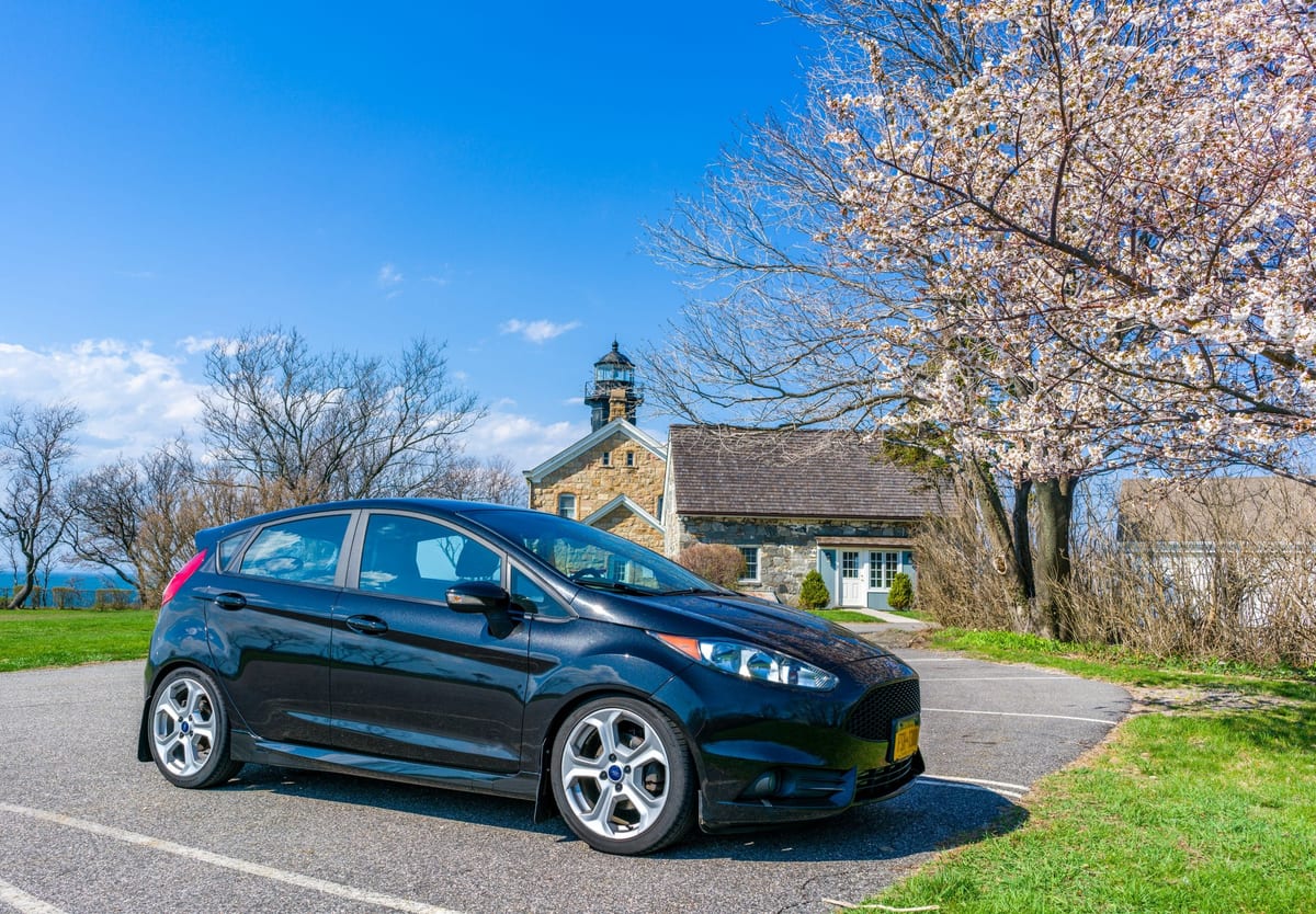 A black ford fiesta parked in front of a church.