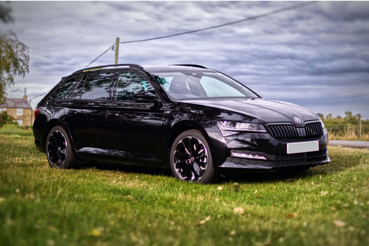 A black skoda estate parked on a grassy field.